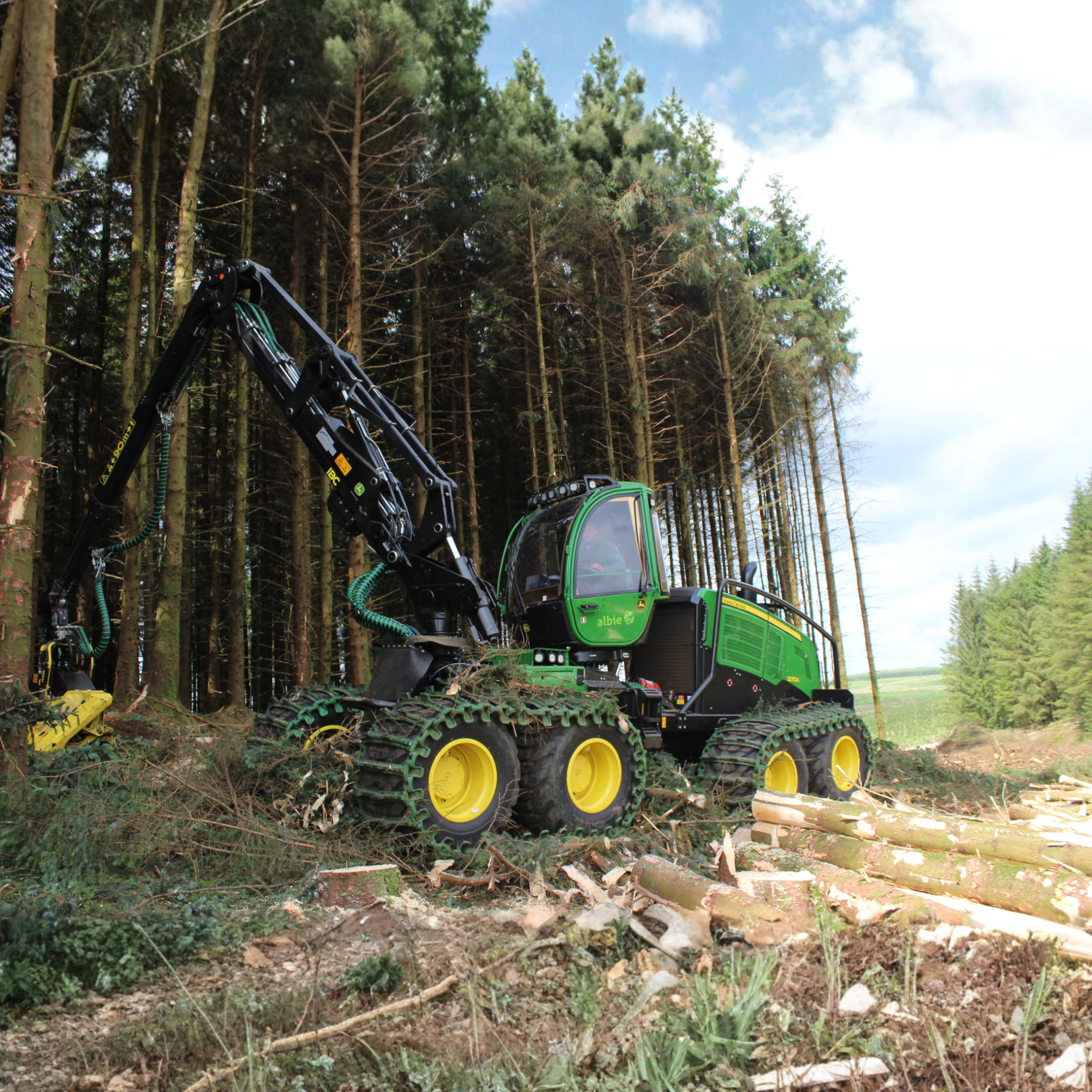Logging machine in a forest clearing with trees and logs around